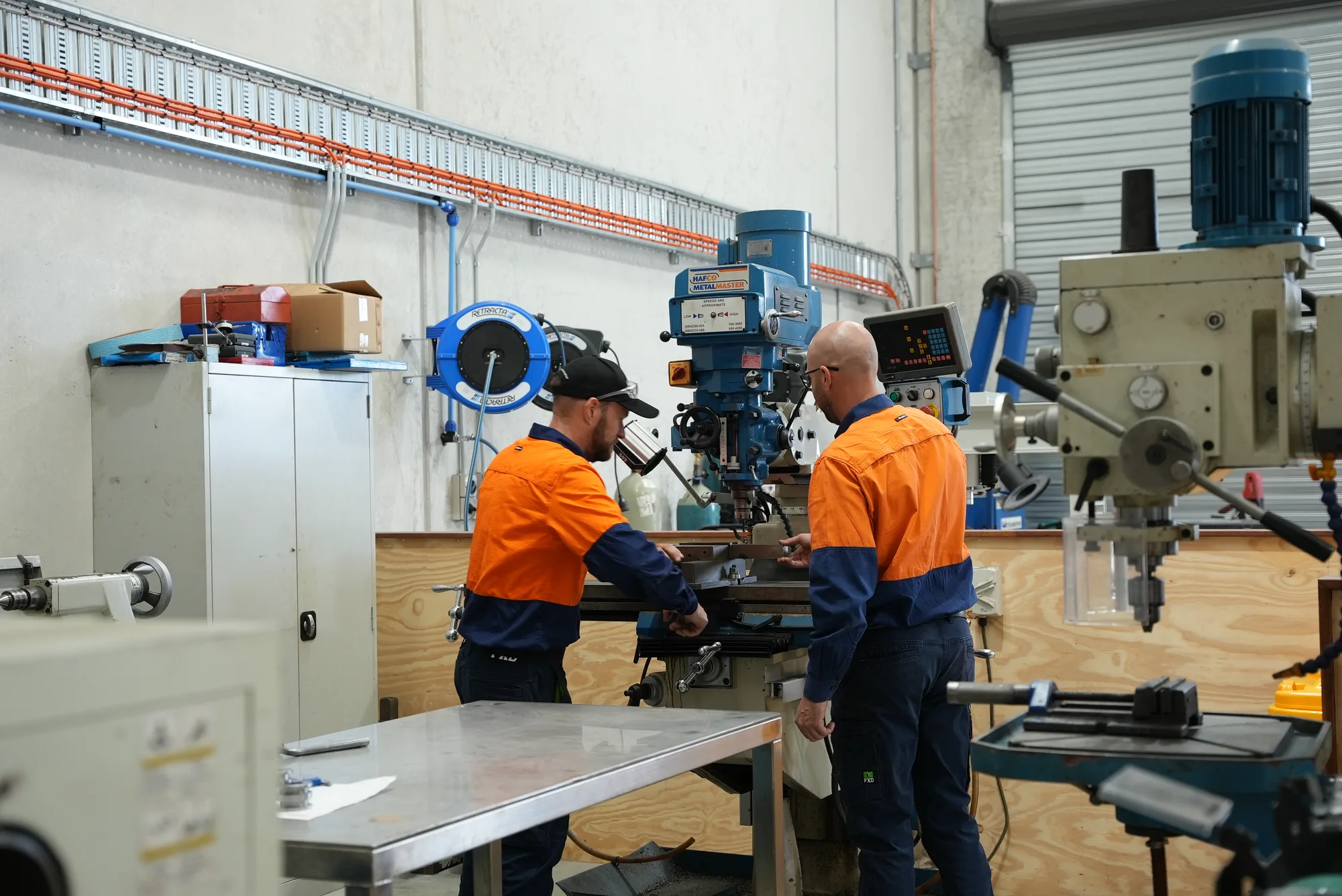 Two AIS team members working together at a milling machine in the workshop
